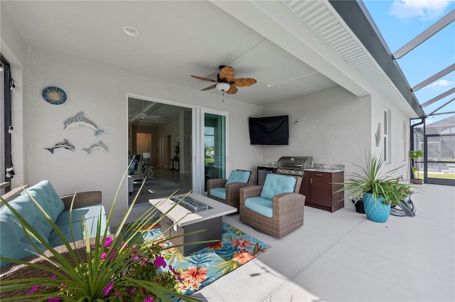 view of patio featuring ceiling fan, glass enclosure, an outdoor fire pit, and area for grilling