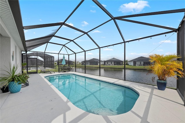 outdoor pool featuring glass enclosure, a patio, and a water view