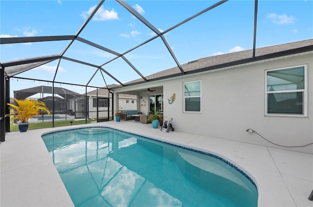 outdoor pool featuring a ceiling fan, glass enclosure, and a patio area