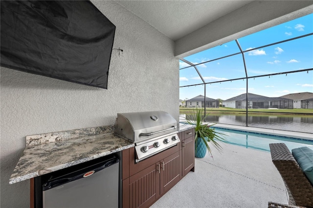 view of patio featuring an outdoor pool, a lanai, a water view, a grill, and exterior kitchen