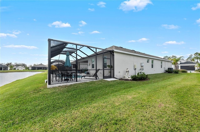 back of house featuring a yard, stucco siding, a water view, a patio area, and glass enclosure