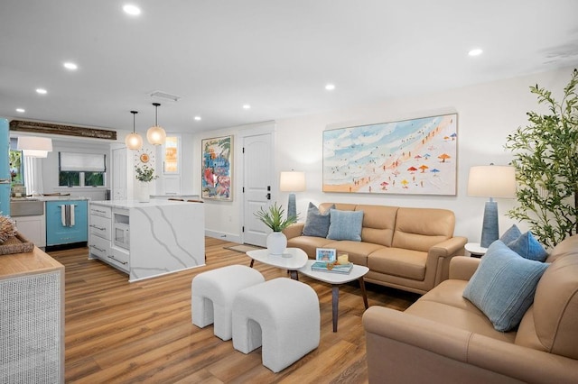 living room with recessed lighting, visible vents, and light wood-style flooring