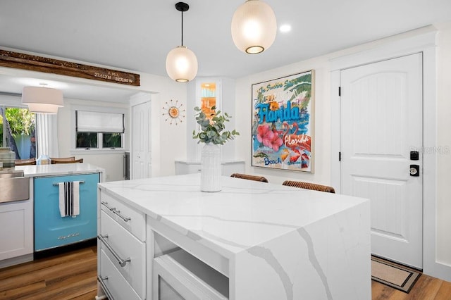 kitchen featuring a kitchen island, pendant lighting, dishwasher, light stone counters, and dark wood-style floors