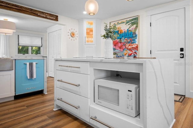 kitchen with white microwave, dark wood-style floors, dishwashing machine, and light countertops