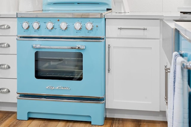 details with white cabinetry, wood finished floors, and range