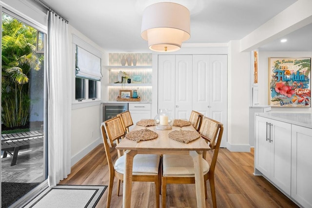 dining room with wine cooler, recessed lighting, light wood-style floors, and baseboards