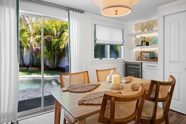 dining area featuring wine cooler, plenty of natural light, a dry bar, and wood finished floors