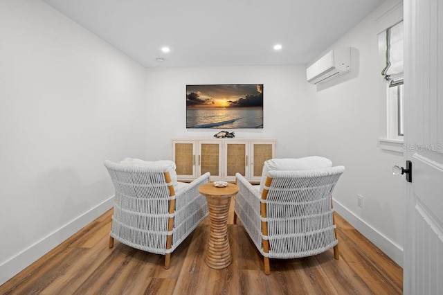 living area with recessed lighting, a wall mounted air conditioner, baseboards, and wood finished floors