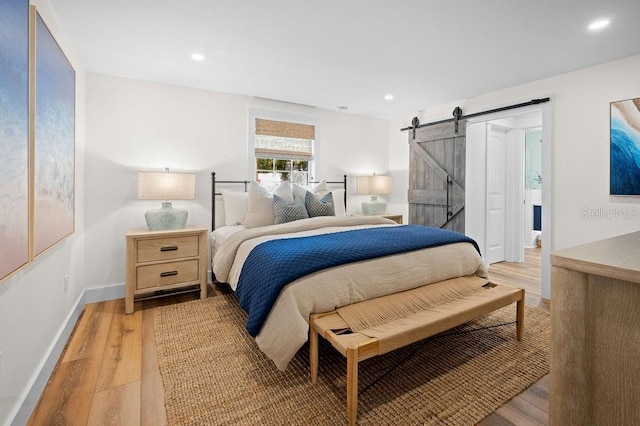 bedroom with light wood-type flooring, a barn door, baseboards, and recessed lighting