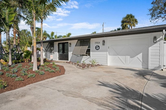 ranch-style house featuring french doors, driveway, and an attached garage