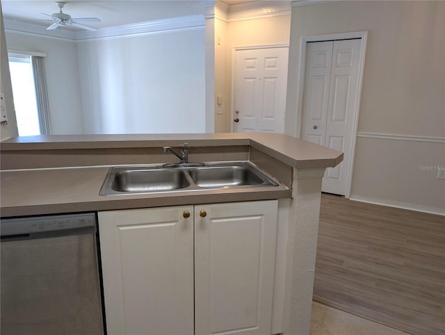 kitchen featuring wood finished floors, a sink, white cabinets, ornamental molding, and stainless steel dishwasher