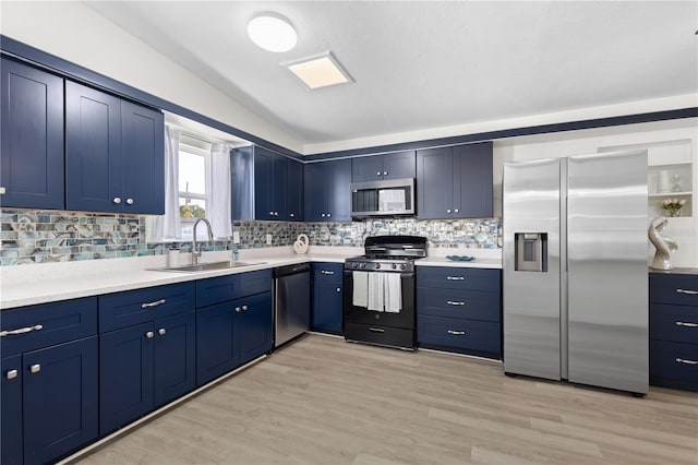 kitchen with blue cabinetry, appliances with stainless steel finishes, a sink, and decorative backsplash