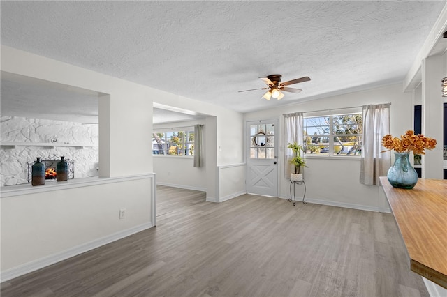 entrance foyer featuring ceiling fan, a textured ceiling, baseboards, and wood finished floors