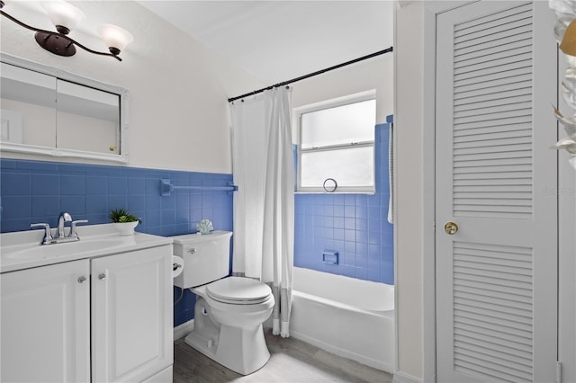 bathroom featuring tile walls, toilet, wainscoting, vanity, and wood finished floors