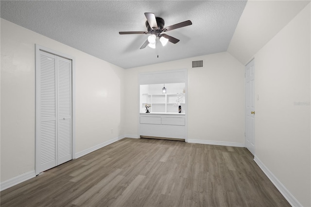 unfurnished bedroom with baseboards, a textured ceiling, visible vents, and wood finished floors