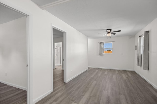 spare room featuring a ceiling fan, baseboards, and wood finished floors