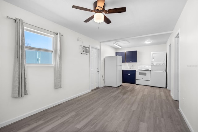 kitchen featuring blue cabinetry, stacked washer / dryer, light wood-type flooring, white appliances, and a wall mounted air conditioner