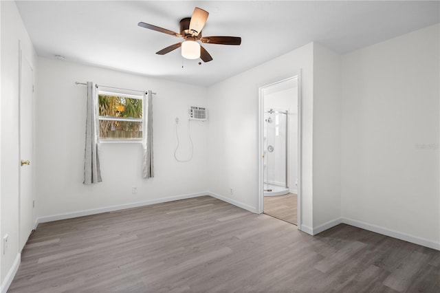 spare room with ceiling fan, a wall mounted AC, baseboards, and wood finished floors