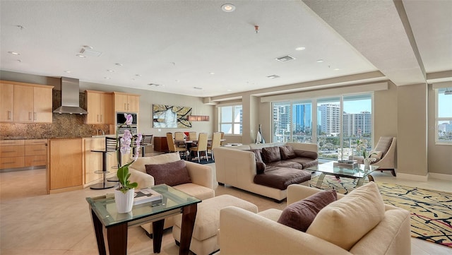 living room featuring baseboards, visible vents, light tile patterned flooring, recessed lighting, and a city view