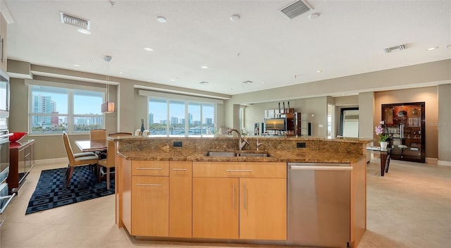 kitchen featuring light stone counters, visible vents, a center island with sink, and appliances with stainless steel finishes