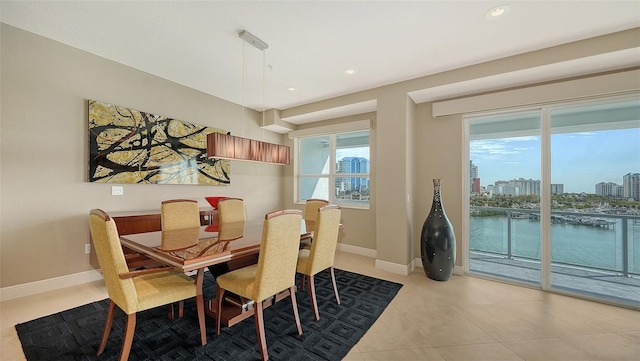 dining area with light tile patterned floors, recessed lighting, a view of city, and baseboards