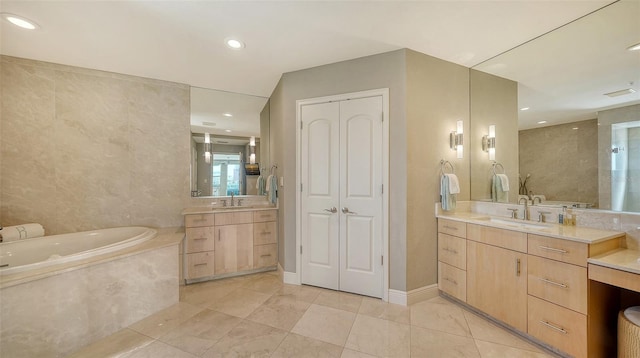 bathroom featuring a bath, recessed lighting, two vanities, and a sink