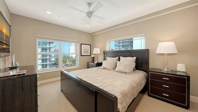 bedroom featuring light carpet, multiple windows, a ceiling fan, and baseboards