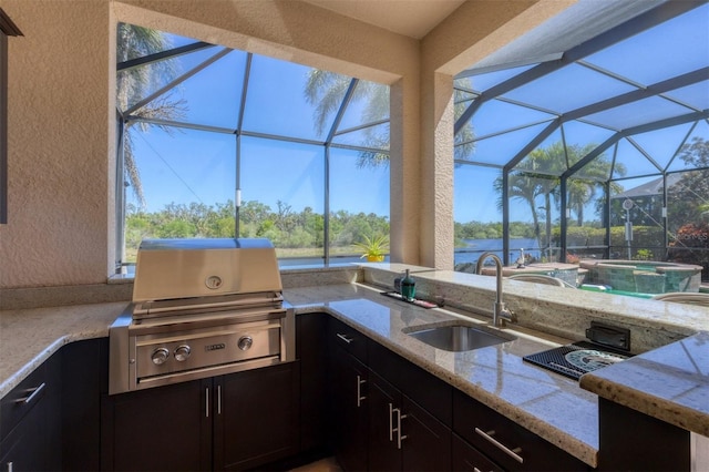 view of patio / terrace with a lanai, outdoor wet bar, area for grilling, a sink, and grilling area