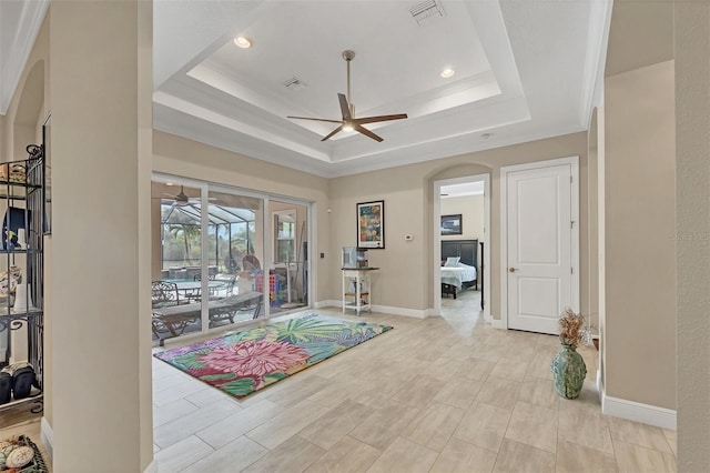 interior space with a ceiling fan, a tray ceiling, and visible vents