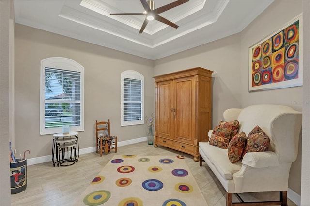 sitting room featuring ceiling fan, a raised ceiling, and crown molding