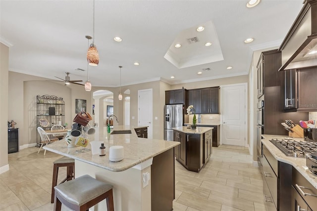 kitchen featuring arched walkways, a spacious island, appliances with stainless steel finishes, custom exhaust hood, and a sink