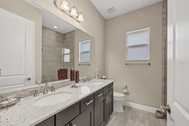 bathroom with toilet, visible vents, a sink, and baseboards