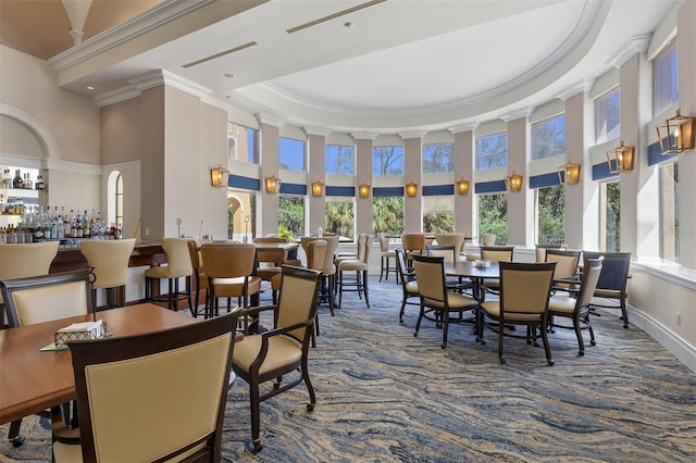 carpeted dining room with baseboards, a tray ceiling, a high ceiling, and crown molding