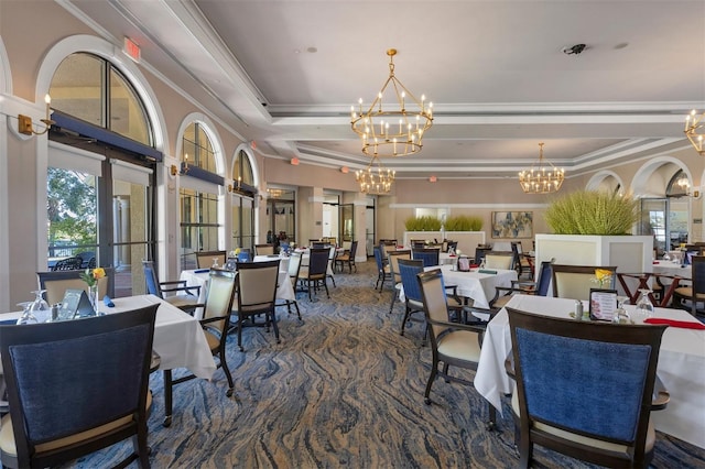 dining space with a chandelier, a tray ceiling, and ornamental molding