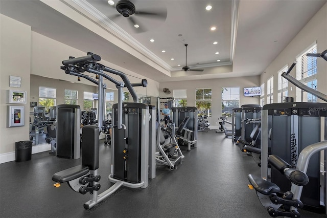 exercise room with baseboards, ornamental molding, a raised ceiling, and a ceiling fan