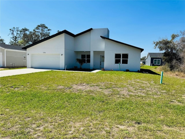 contemporary home featuring a garage, concrete driveway, a front yard, and stucco siding