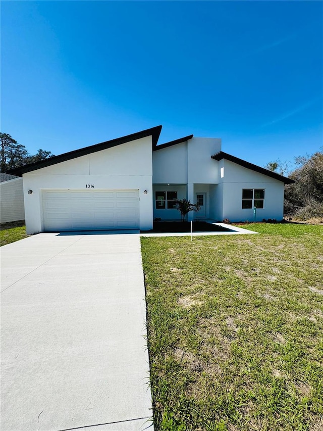 view of front facade featuring a garage, concrete driveway, a front lawn, and stucco siding