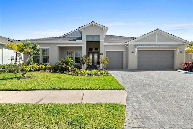 view of front of property featuring decorative driveway, french doors, stucco siding, a front yard, and a garage