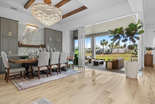 dining space with light wood-style floors, visible vents, a chandelier, and beamed ceiling