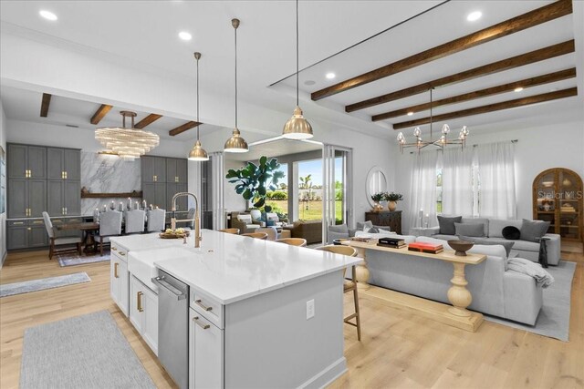 kitchen with dishwasher, open floor plan, light wood-style floors, a chandelier, and a sink