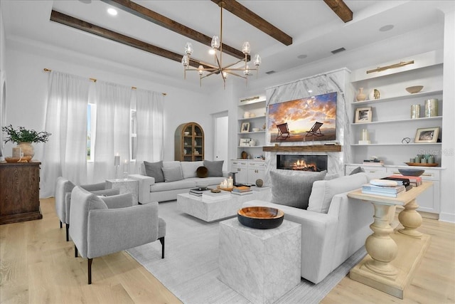 living area with built in shelves, beam ceiling, a fireplace, light wood finished floors, and visible vents