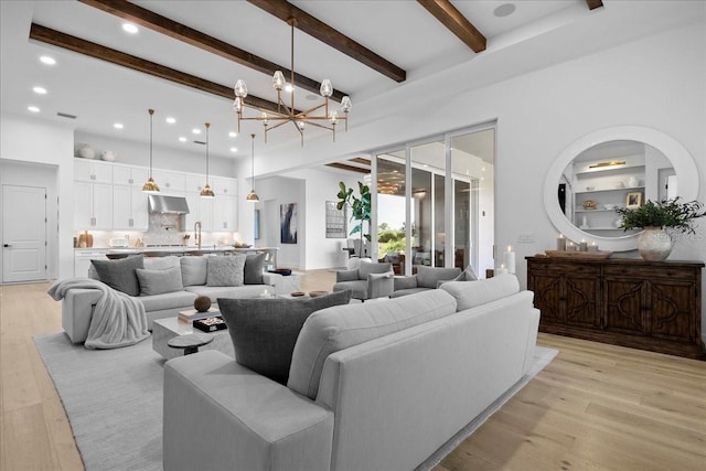 living area with built in shelves, light wood-style flooring, beam ceiling, and a notable chandelier