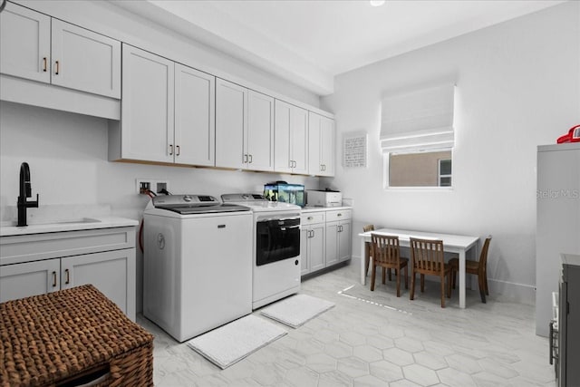 washroom featuring cabinet space, a sink, and washer and clothes dryer