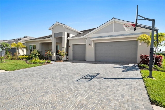 view of front facade featuring a garage, decorative driveway, and stucco siding