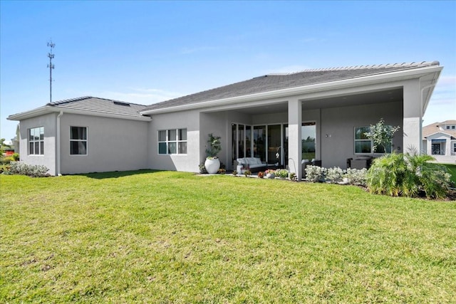 rear view of property featuring a lawn and stucco siding