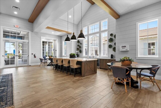 dining area featuring high vaulted ceiling, light wood-style flooring, visible vents, french doors, and beamed ceiling