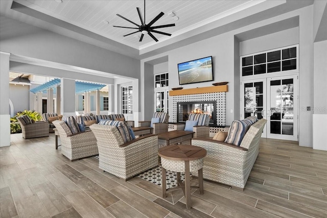 interior space featuring a raised ceiling, a ceiling fan, a high ceiling, wood finish floors, and a fireplace