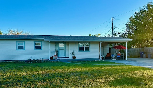 ranch-style home featuring driveway, fence, a carport, and a front yard