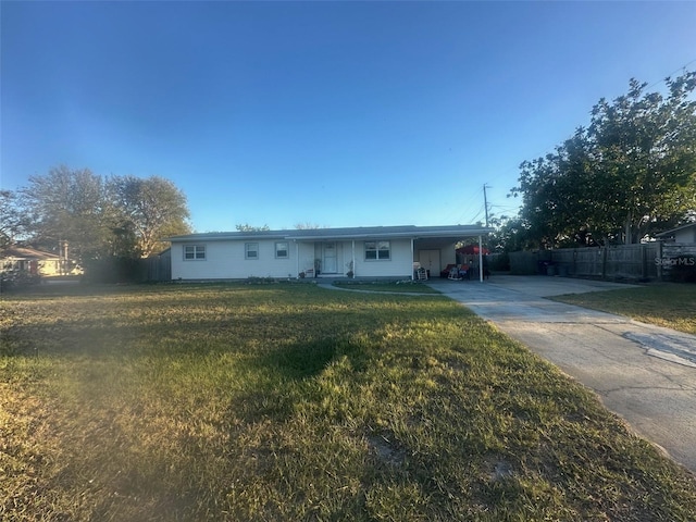 ranch-style home with an attached carport, concrete driveway, fence, and a front yard