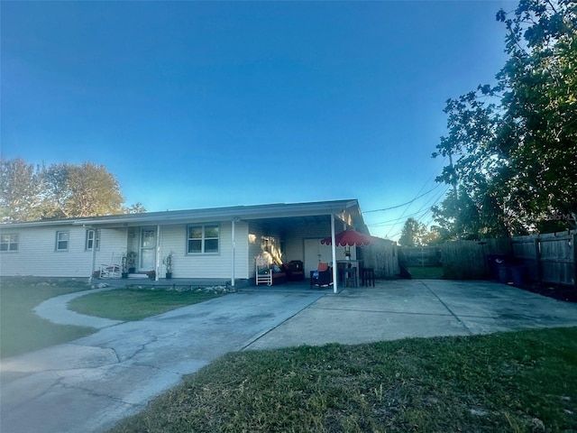 back of property featuring concrete driveway, an attached carport, a patio area, and fence